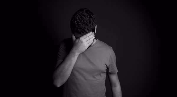 Man with hand over face appears to be sad